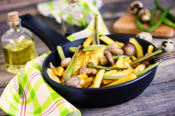 fried potatoes with mushrooms and asparagus in a pan on a wooden board