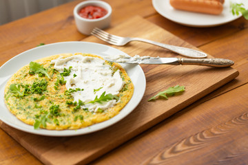 Omelette with herbs, soft cheese, grilled sausages and tomato sauce. Delicious breakfast