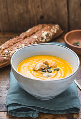 Butternut squash cream soup bowl. Roasted pumpkin soup with pumpkin seeds on rustic wood background.