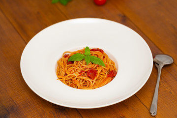 Plate of delicious Italian spaghetti pasta with fresh basil leaves,  with meat, tomato sauce, vegetables and grated parmesan cheese