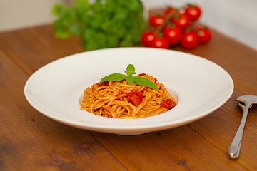 Plate of delicious Italian spaghetti pasta with fresh basil leaves,  with meat, tomato sauce, vegetables and grated parmesan cheese