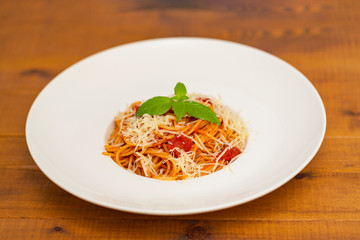 Plate of delicious Italian spaghetti pasta with fresh basil leaves,  with meat, tomato sauce, vegetables and grated parmesan cheese