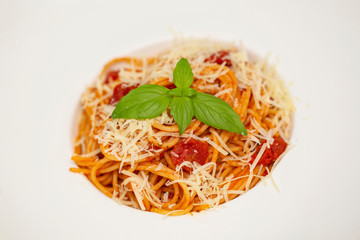 Plate of delicious Italian spaghetti pasta with fresh basil leaves,  with meat, tomato sauce, vegetables and grated parmesan cheese