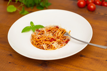 Plate of delicious Italian spaghetti pasta with fresh basil leaves,  with meat, tomato sauce, vegetables and grated parmesan cheese