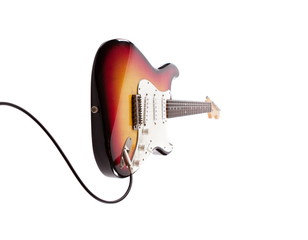 Sunburts double cutaway elctric guitar plugged in, isolated on white.
