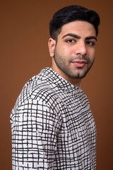 Young handsome Indian man against brown background