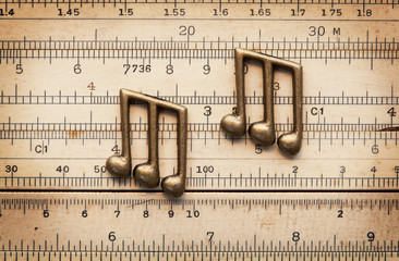 Musical timing, rhythm. beat and groove, concept image. Brass notes on a vintage calculation rule.