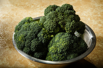 raw green broccoli lies in metal bowl