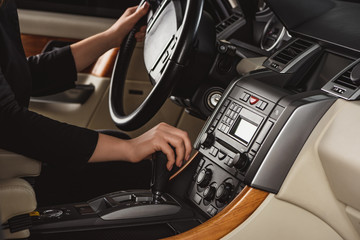 Fototapeta premium Cropped shot of woman changing gear while driving new car