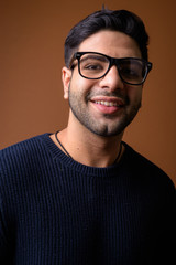 Fototapeta premium Young handsome Indian man against brown background