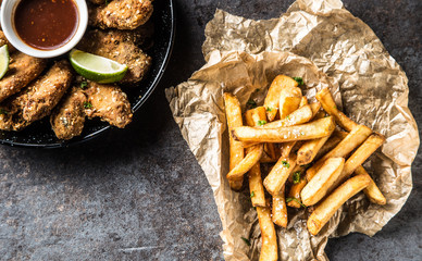 Fried chicken wings chili sauce lime and potato fries.