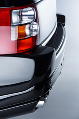 Close up view of rear headlight of luxury black car on grey backdrop