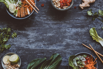 Delicious asian bowls with rice noodles, vegetables and tofu on wooden background with copy space. - obrazy, fototapety, plakaty