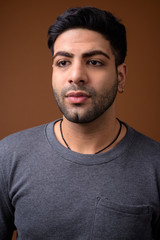 Young handsome Indian man against brown background