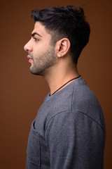 Fototapeta premium Young handsome Indian man against brown background