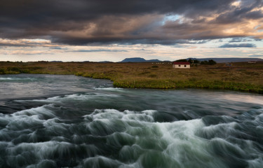 Typical Rural Icelandic house at river Coastline. Horizontal shot at the sunset
