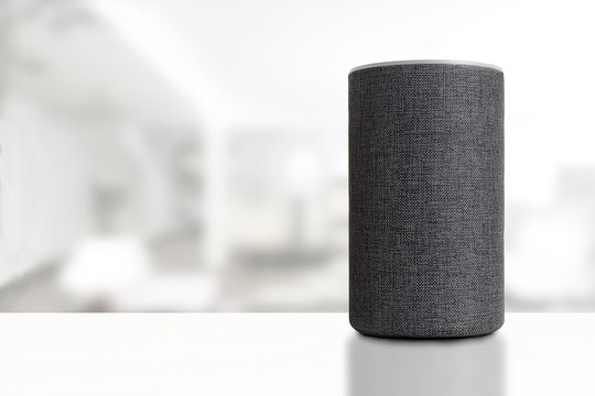 Personal assistant loudspeaker on a white wooden shelf of a smart home living room. Empty copy space for Editor's text.