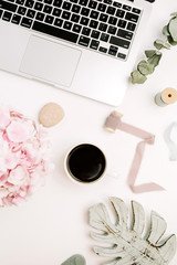 Modern home office desk on white background. Laptop, coffee mug, pink hydrangea flower bouquet, eucalyptus, monstera. Flat lay, top view woman workspace.