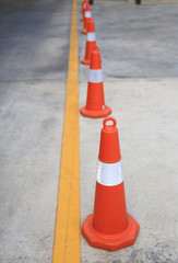 Row of orange rubber traffic cone placed in road.