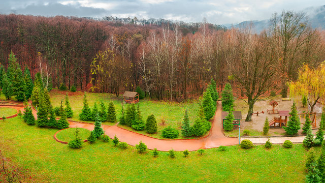 park with playground in autumn. gloomy rainy weather in mountains. green lawn and leafless forest in november