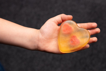 Hand holds handmade soap in the form of a heart.