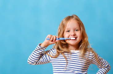 A little girl in striped pajamas is brushing her teeth with a toothbrush. The concept of daily...