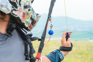 Close-up of a professional paraglider holding brakes and looking away. Paraglider sport concept