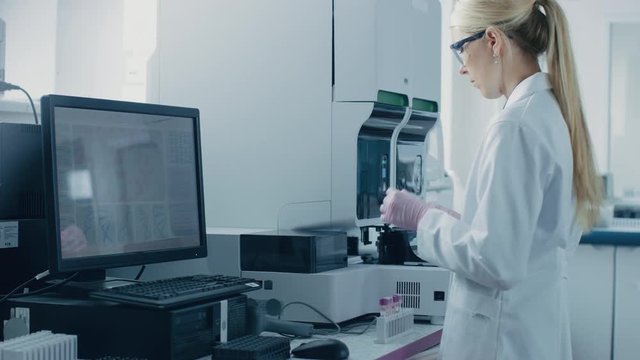 Female Research Scientist Puts Test Tube with Blood Sample into Medical Analyzing Machine. Scientist Works in Innovative Pharmaceutical Genetic Research Laboratory.