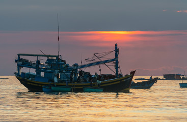 Mui Ne, Vietnam - September 28, 2018: Sea view at dawn when sunrise horizon, fishermen transport sea fish from the boat to shore trade for their family in coastal fishing village in Mui Ne, Vietnam