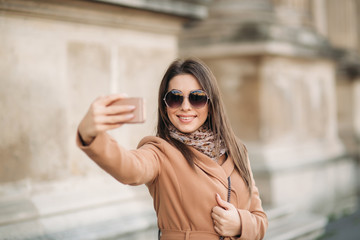 Beautiful girl in sunglasses make photo on smartphone. selfie