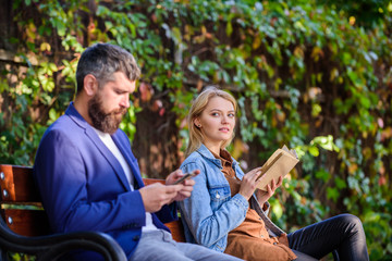 Woman read book while man read ebook smartphone. Man with beard and woman read alternative information storage. Read book in park pleasant leisure. Interesting literature. Reading hobby concept
