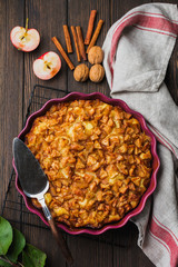 Apple and cinnamon homemade pie with walnuts and custard on an old concrete background. Rustic style. Top view.