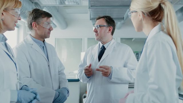Team of Research Scientists Have Meeting, They Have Discussion While Standing in the Middle of Laboratory