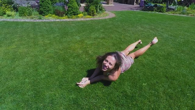Smiling beautiful woman rolls over on grass joyfully playing flirting carefree