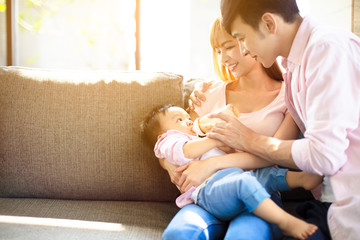 happy father and mother feeding baby from bottle