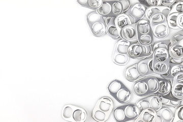 aluminium ring pull opener or ring tabs on white background, free space for text in middle. concept : recycle ringpulls for disable prostheses.