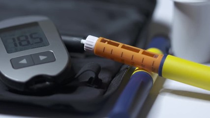 Diabetes testing equipment and insulin therapy. Hyperglycemia. Diabetic pens and glucose meter. High blood sugar level is 18.5 mmol/L 333.33 mg/dL on display of glucometer.