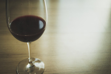 Red wine in wineglass against wooden background.