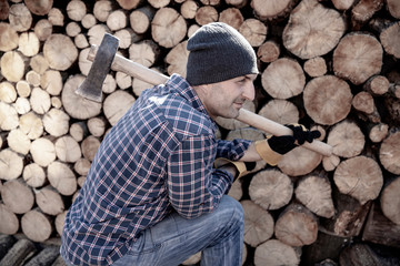 Man holding an industrial ax. Ax in hand. A strong man holds an ax in his hands against the background of chainsaws and firewood. Strong man lumberjack with an ax in his hand. Chainsaw close up.