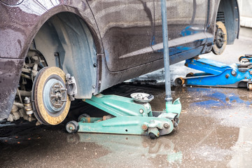 Fototapeta premium The process of replacing summer tires with winter tires. The car is on leveling jacks on the asphalt.