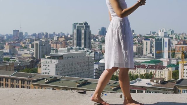 Reckless woman in white dress walks on edge abandoned building suicide daredevil