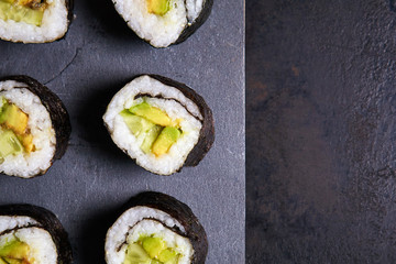 Vegan sushi rolls made with nori algae, sushi rice, cucumbers and avocado. Top view with copy space