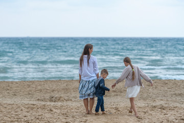 mother and her daughter and son having fun on the beach