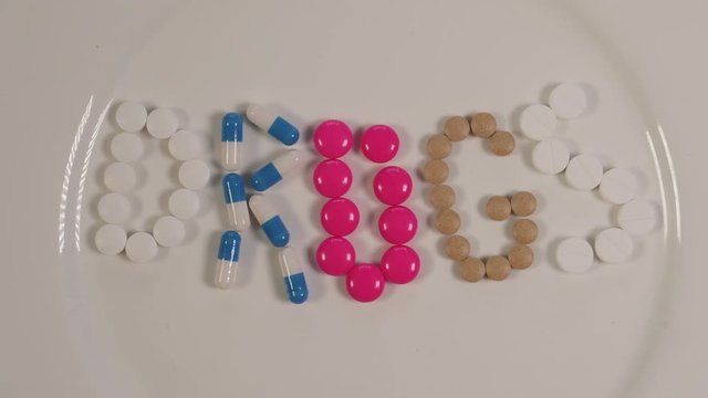Animation with pills forming the word DRUGS.