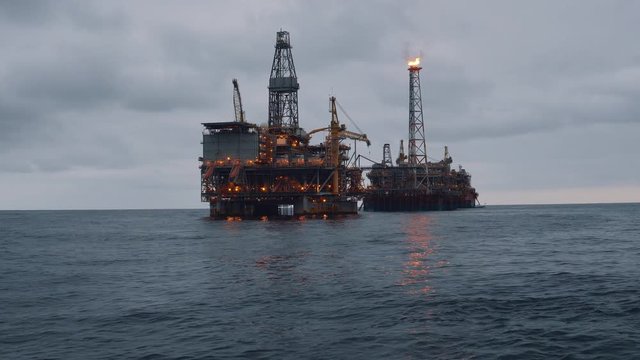 FPSO tanker vessel near Oil Rig platform. Offshore oil and gas industry. Flare is burning with smoke. Environmental pollution