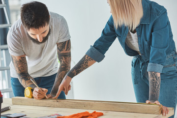 young couple working with wooden plank and measuring tape