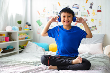 Young asian boy is smiling and listening to music