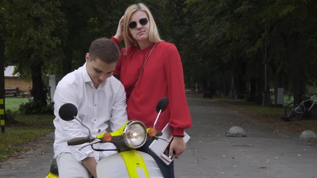 Handsome guy on a scooter is talking to a girl