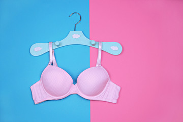 Bra on hanger on blue pink background