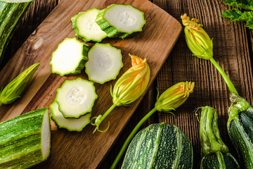 Fresh zucchini and slices of zucchinis on wooden table. Sliced courgette, healthy vegan diet or vegetarian food, cooking concept.